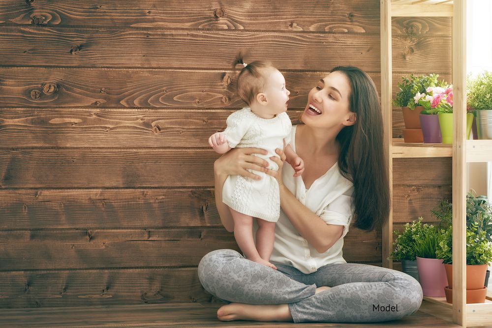 A happy mother with her baby who may be a candidate for a mommy makeover.