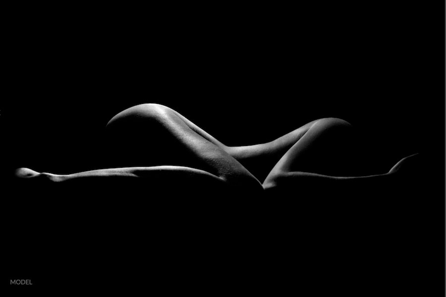 Silhouette of a shapely woman's nude body on black backdrop.