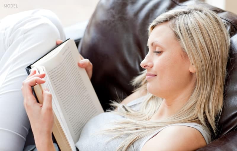 woman reading a book sitting on a sofa in a living-room